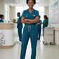 Nurse in teal scrubs standing in a hospital corridor with colleagues in the background